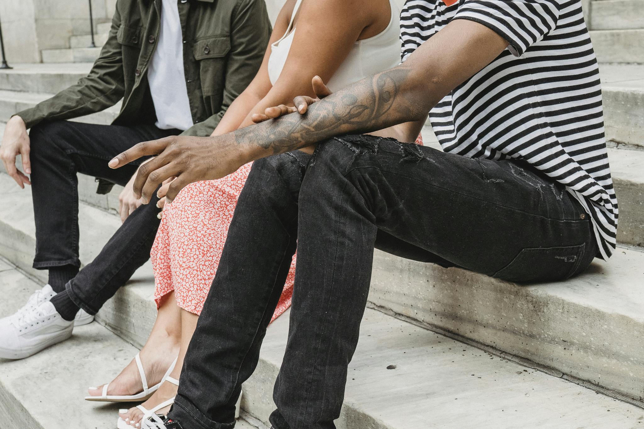 Crop faceless multiethnic millennials relaxing on steps